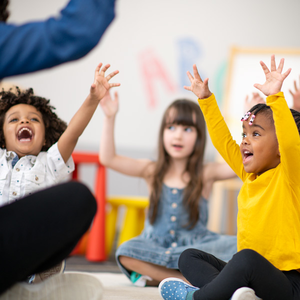 children raising their arms with teacher